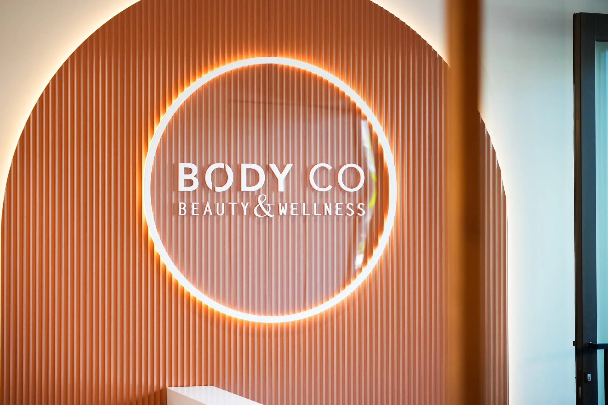 Halo-lit Body Co sign on terracotta fluted panel, Oran Park