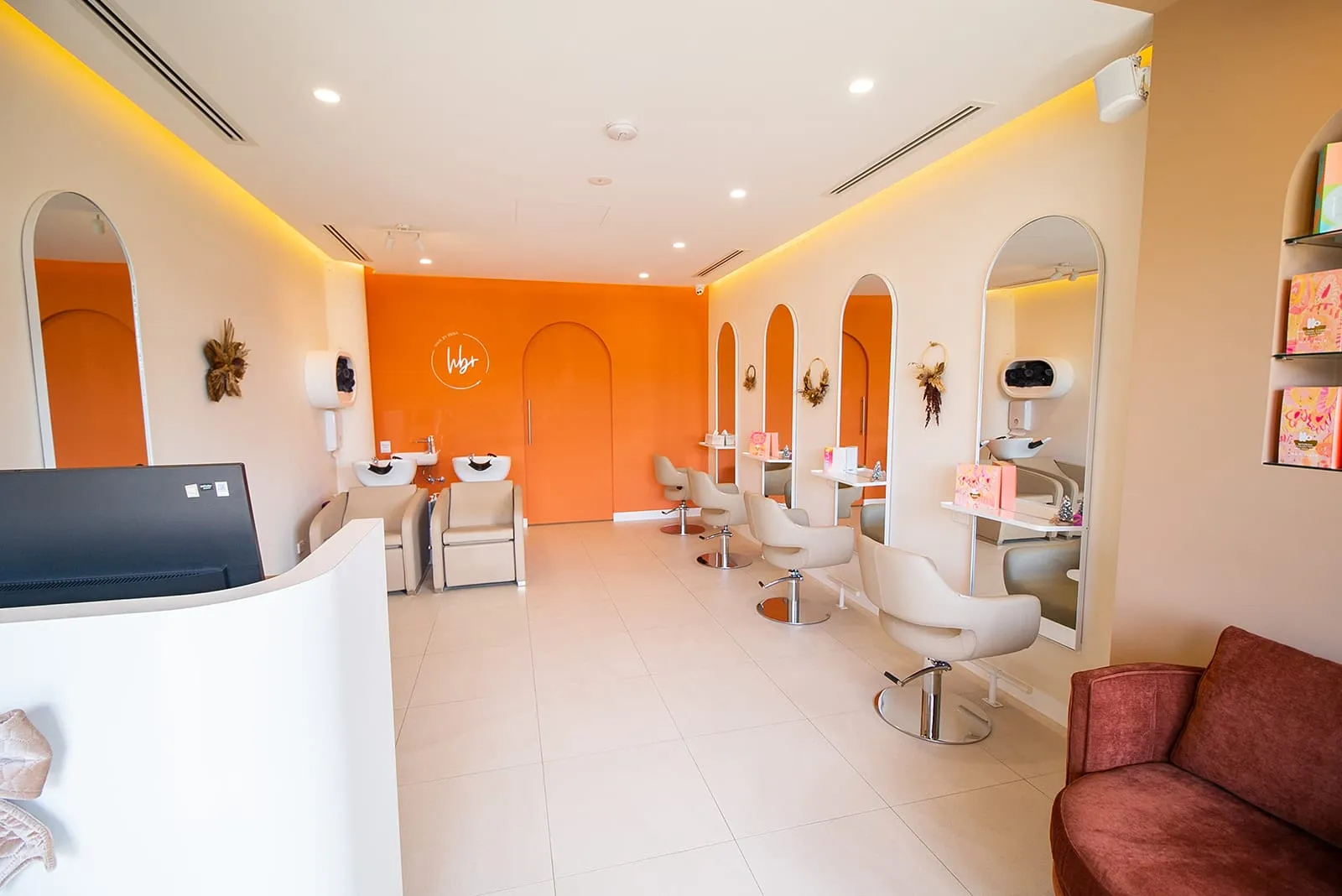 Salon floor with orange feature wall and styling chairs at Hair By Rena, Gregory Hills
