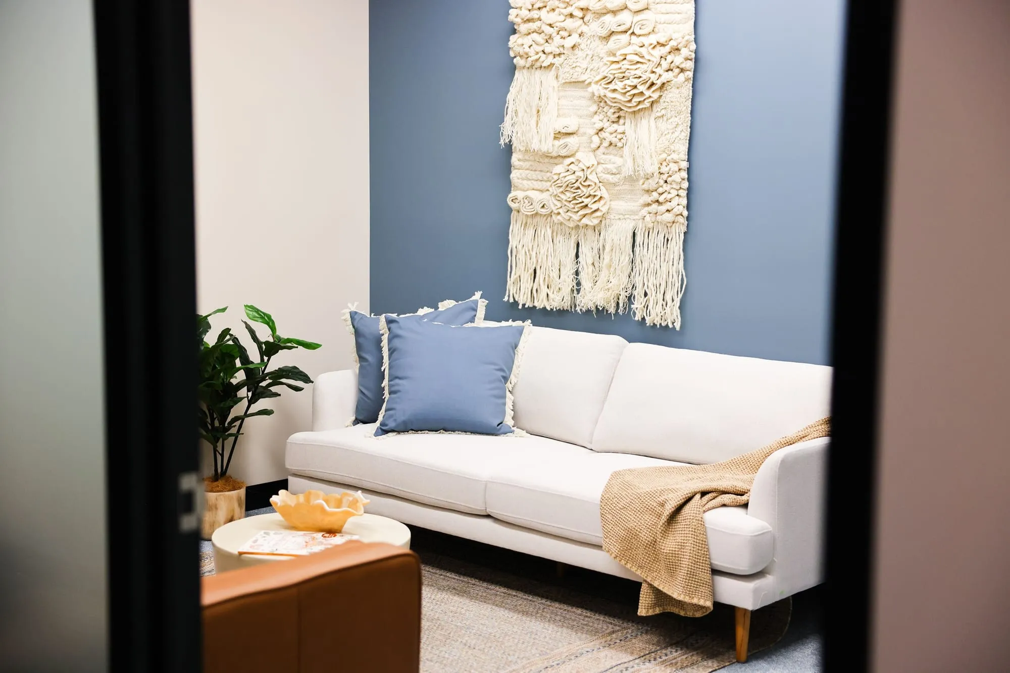 Lounge with sofa and woven wall art at HelpAhead, Caringbah