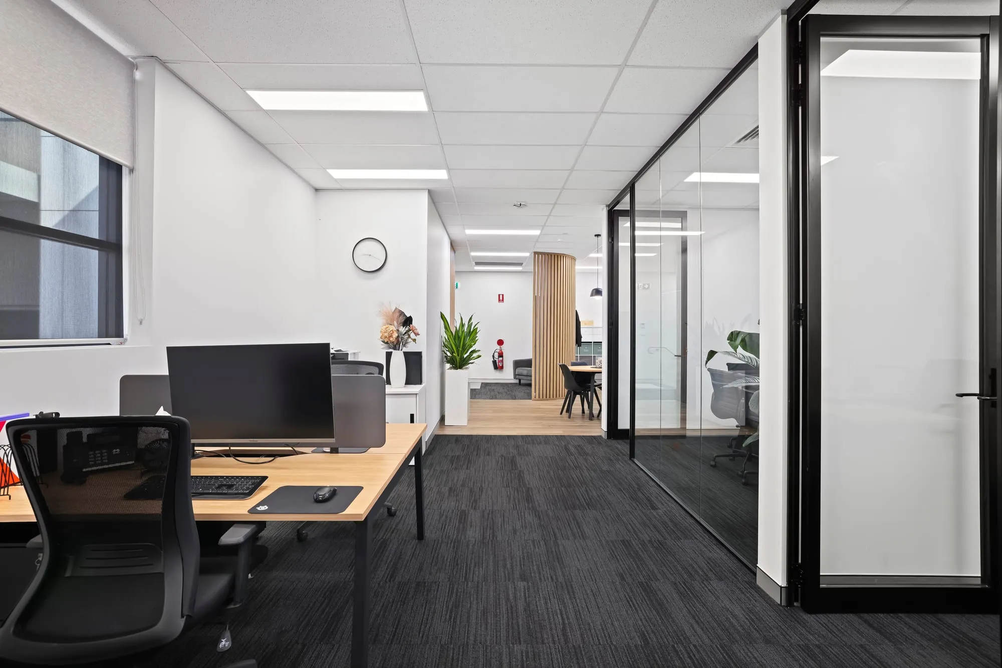 Office workstations beside a glazed meeting room at Macarthur Care, Narellan