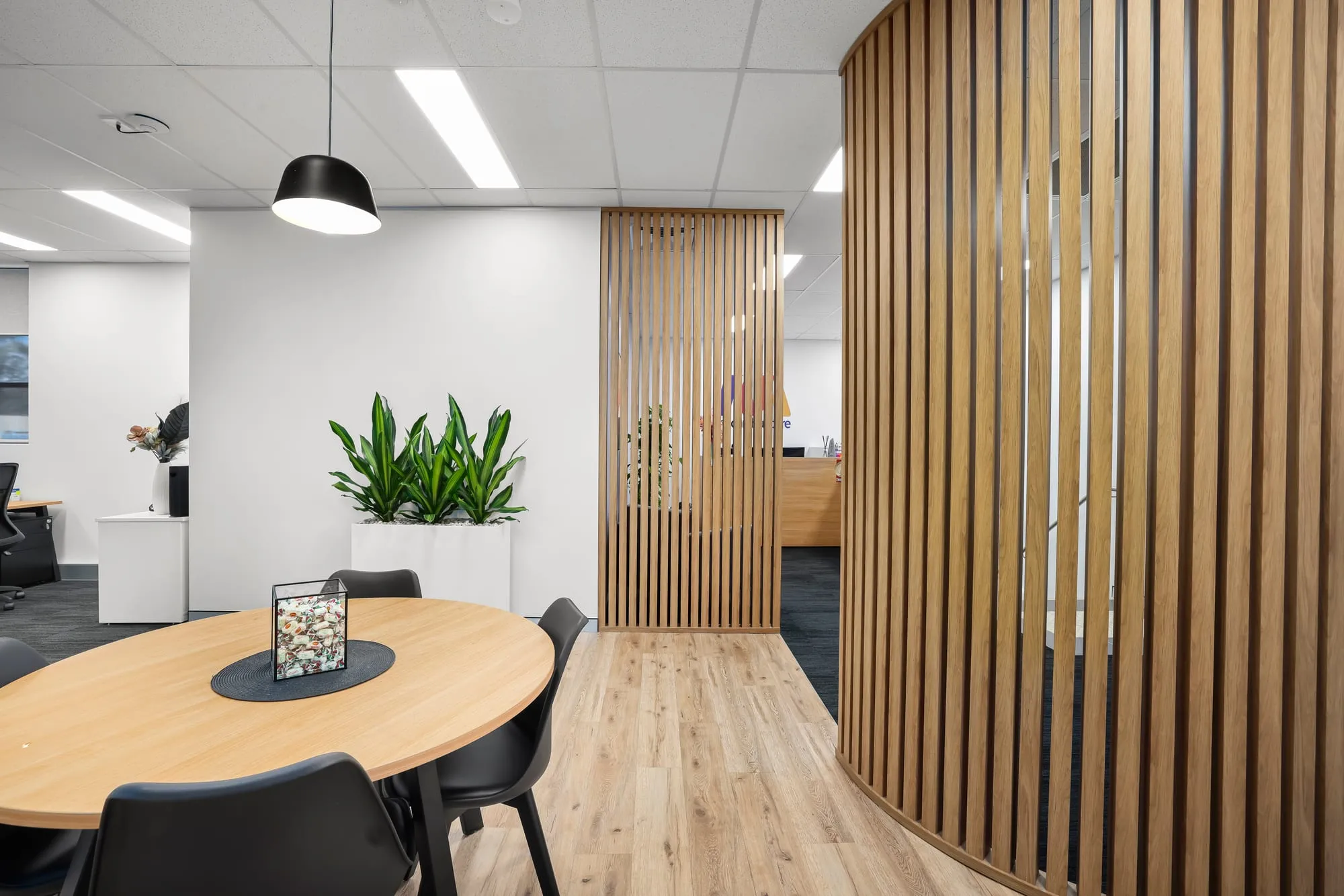 Meeting table beside curved timber-slat screen at Macarthur Care, Narellan